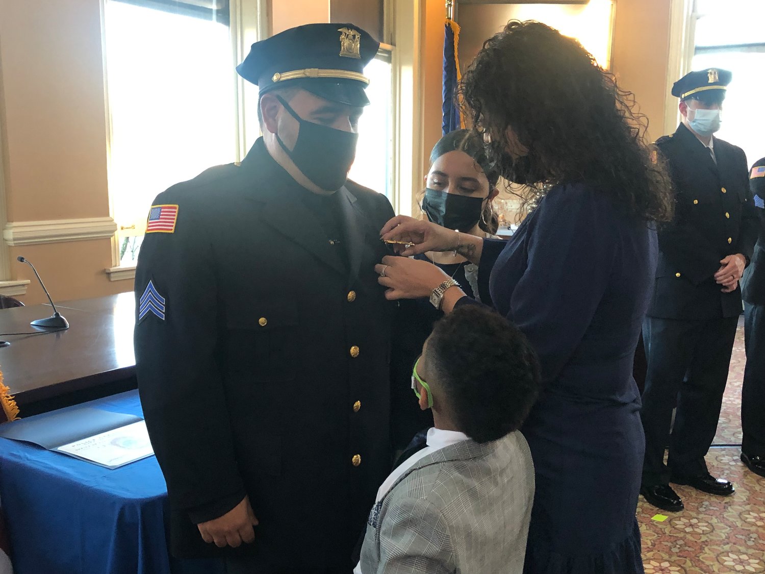 Sergeant Daniel D’Elicio receives his new badge pinned by his wife, daughter and son.